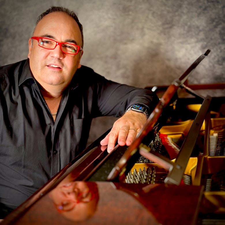 Image of Malcolm Quiney sat at his Steinway Grand Piano